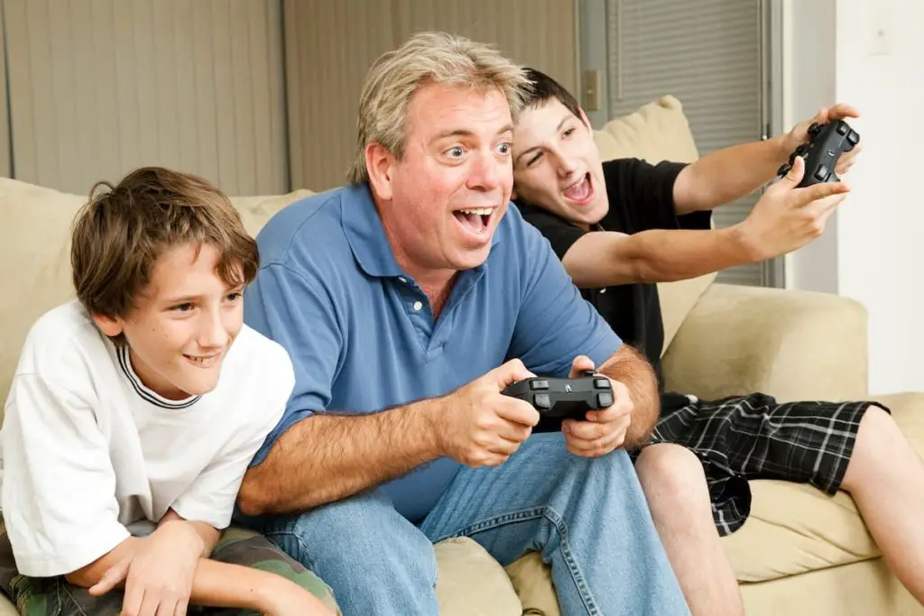 Father and sons playing video games on the couch