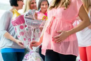 Woman holding stomach at baby shower with friends in background