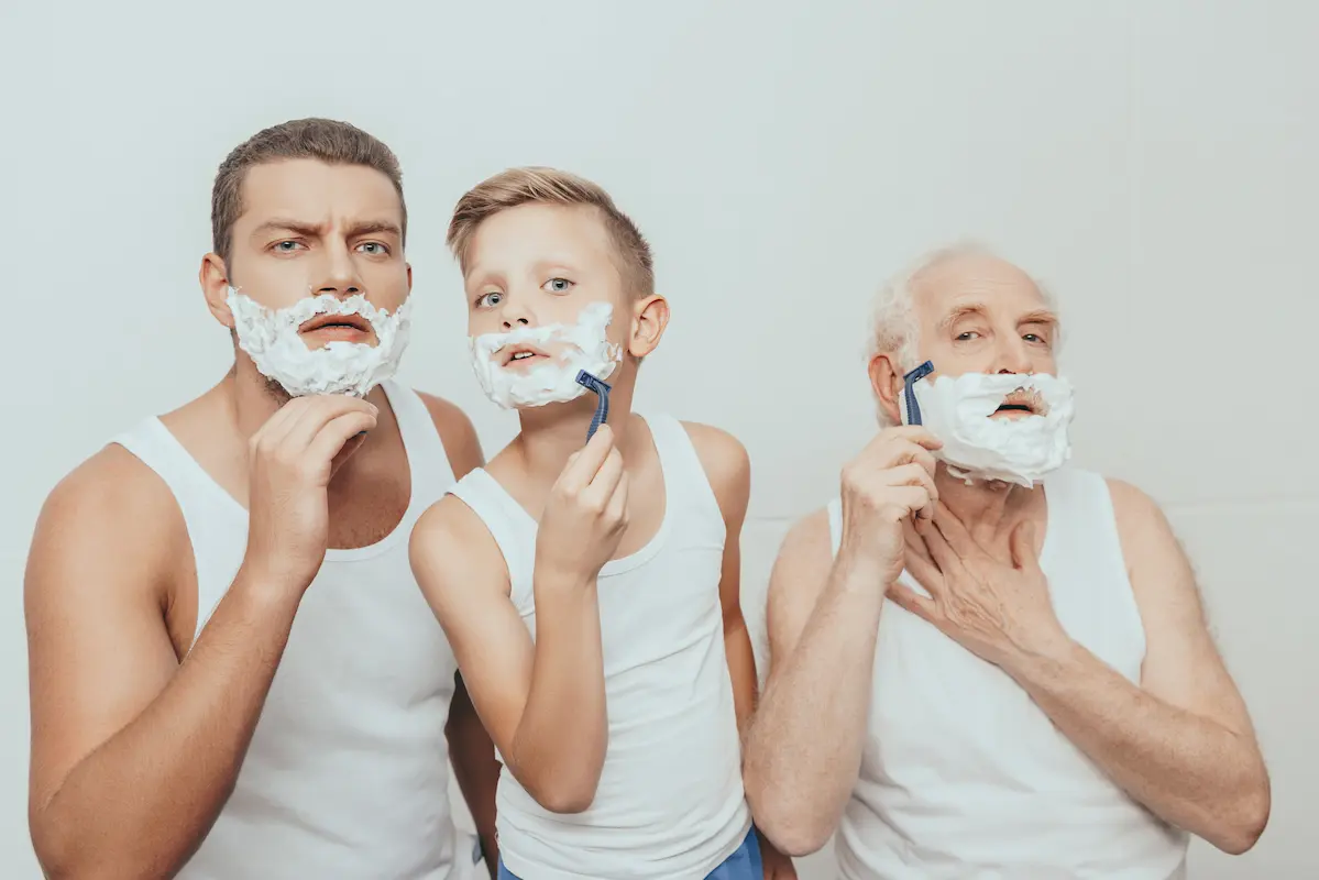 Three generations of men looking in the mirror shaving