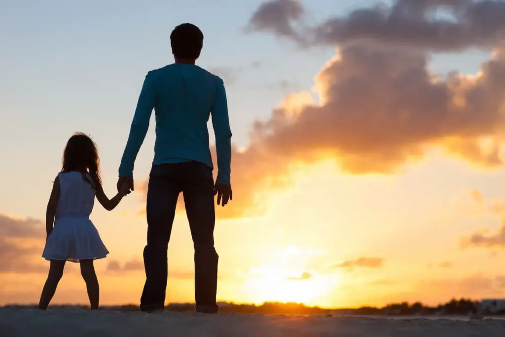 father and daughter holding hands at sunset