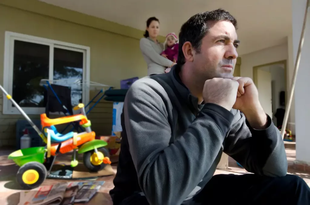 Angry husband sitting on steps on the front of house after telling his wife to leave