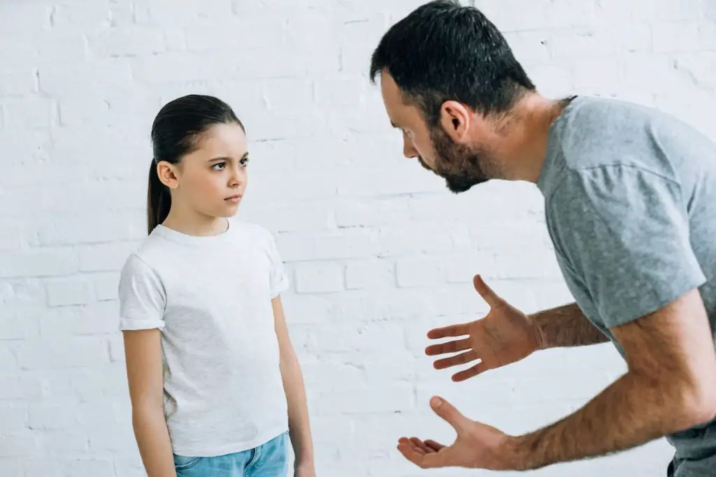 Dad blaming daughter by leaning down and talking seriously to her
