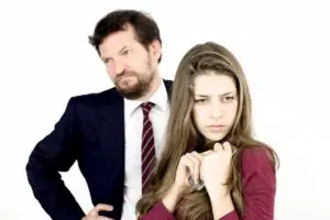 Angry father looking off to the side with upset daughter in front of him