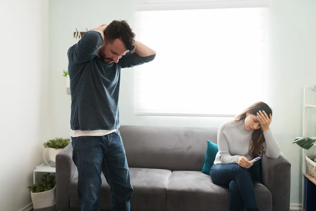 Expectant father experiencing anxiety after him and wife receive positive pregnancy test in living room