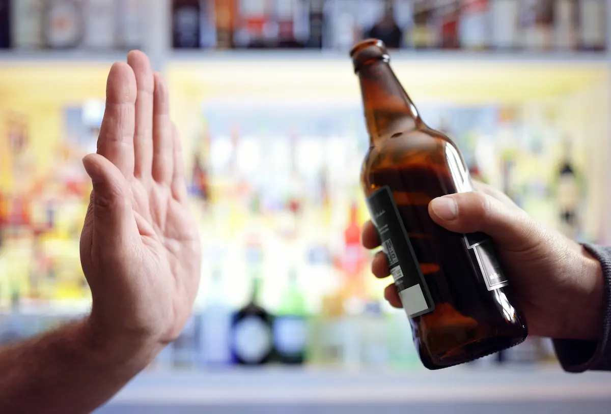 A parent putting their hand up saying no to a beer and yes to being a sober parent