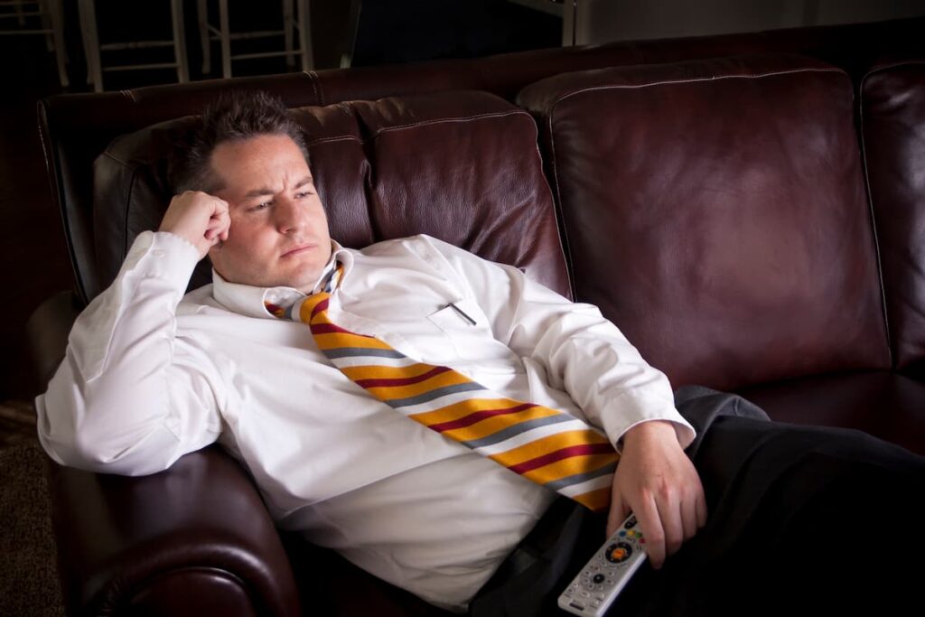Sedentary man with work suit sitting on couch staring at TV