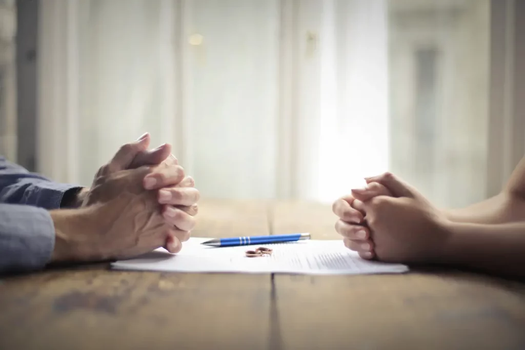 Divorce paper work on table with hands on either side as couple gets ready to tell in-laws