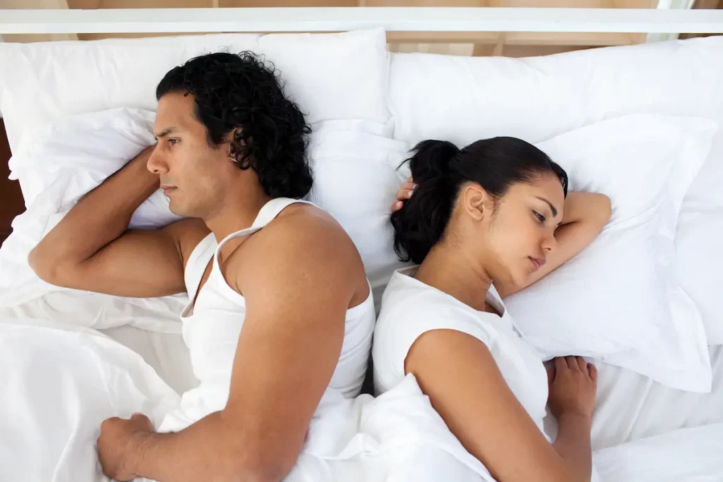 Wife with back to husband in bed because he never initiates intimacy