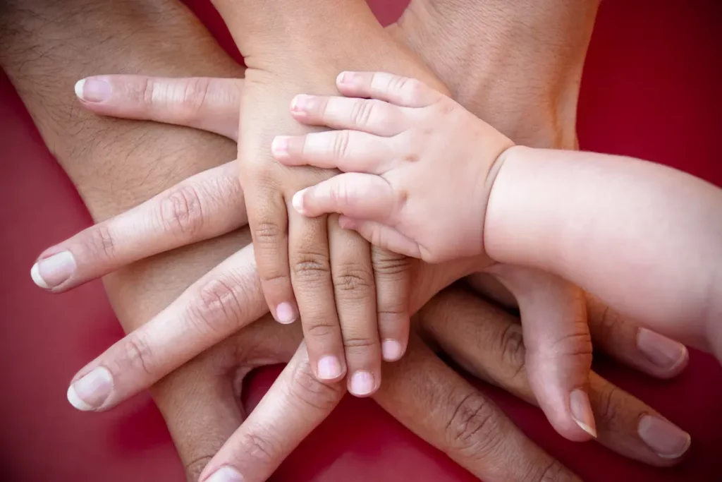 Close up of 4 different hands stacked on top of each other to show importance of family support