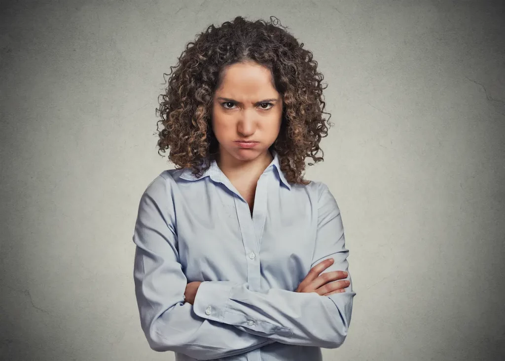 Wife with arms crossed looking cold on grey background