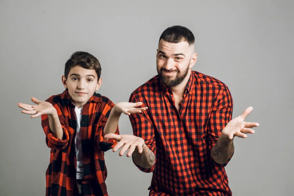 Father and son standing with arms shrugging wondering the difference between father and dad