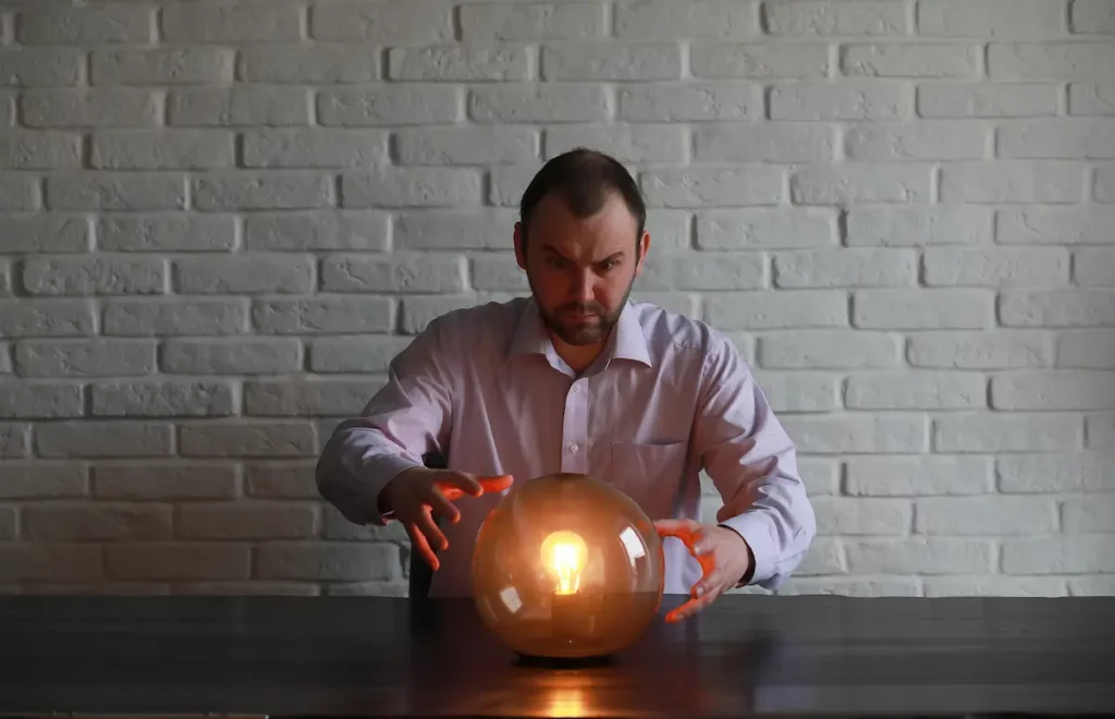 Man with hands around glowing glass ball trying to summon a spell