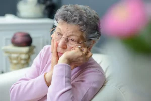 Elderly woman grieving in chair alone after her husband died unexpectantly