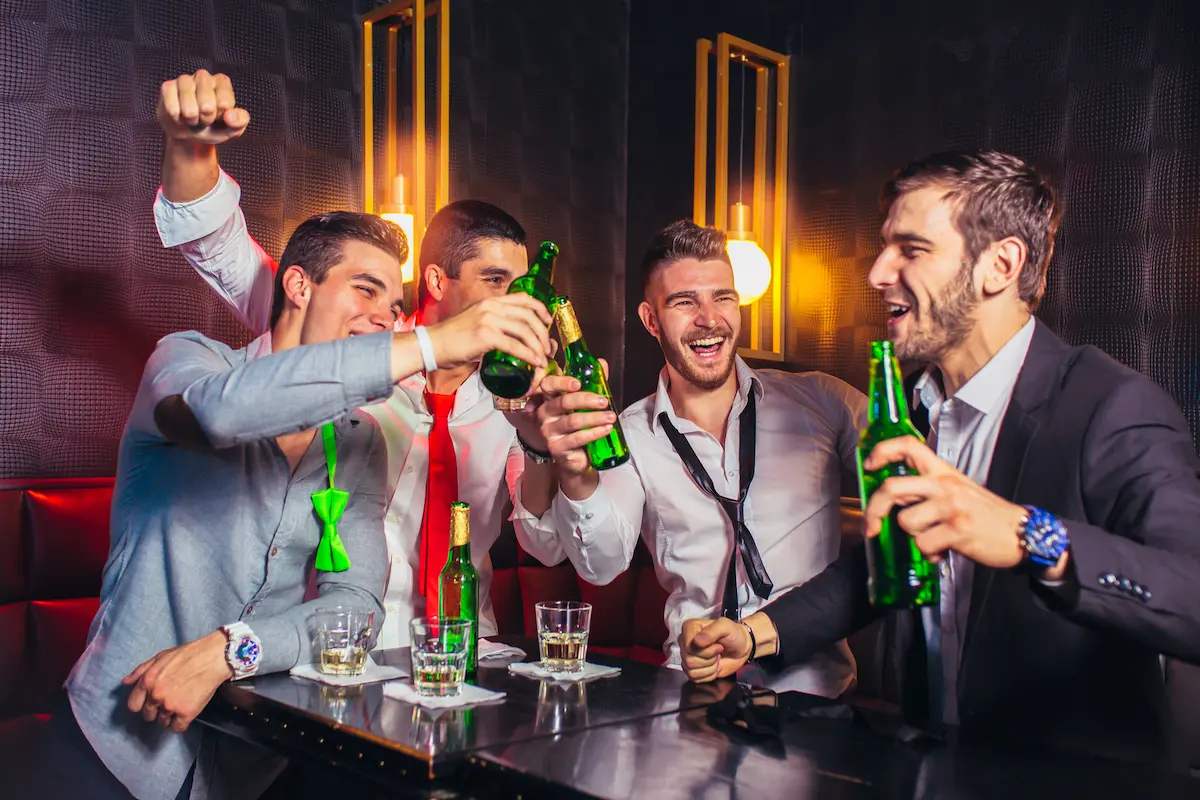 Groupe of four men celebrating at a bachelor party by drinking at a bar