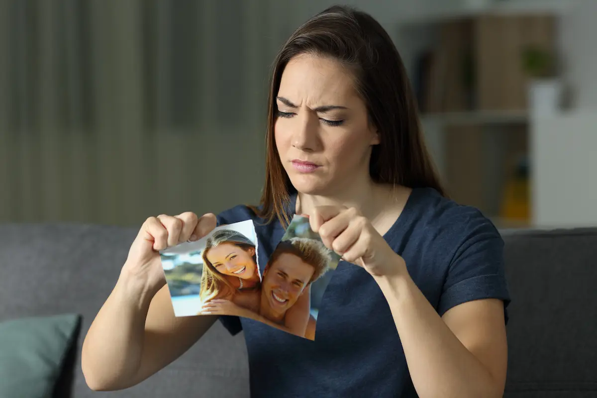 Close up of woman still angry after divorce ripping up photo of her and ex