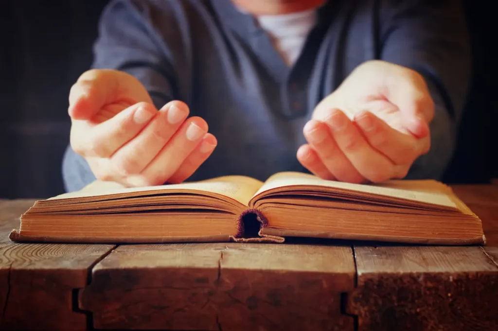 Man holding hands over holy book symbolizing "Forgive me father"