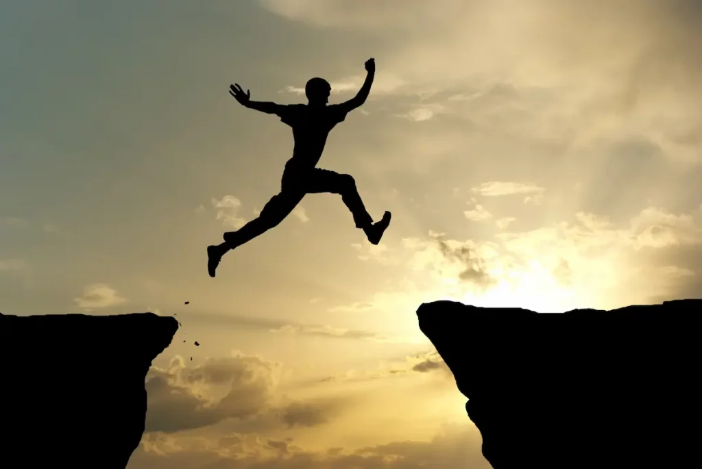 Shadow of man jumping between high mountains, symbolizing happiness after divorce