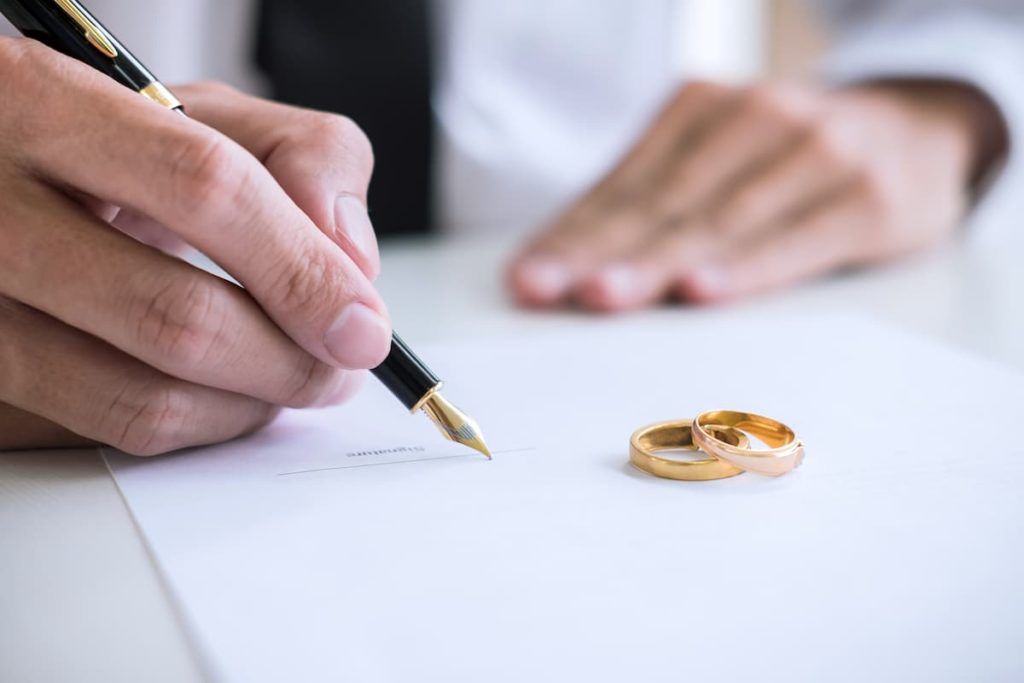 man with wedding rings on table files for divorce with paperwork