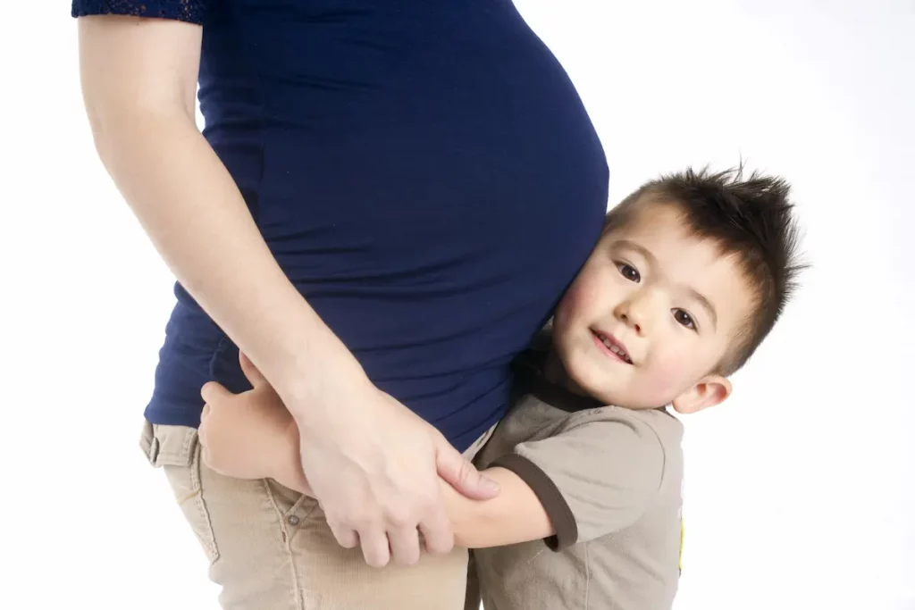 new addition to family as toddler hugs mom's baby bump