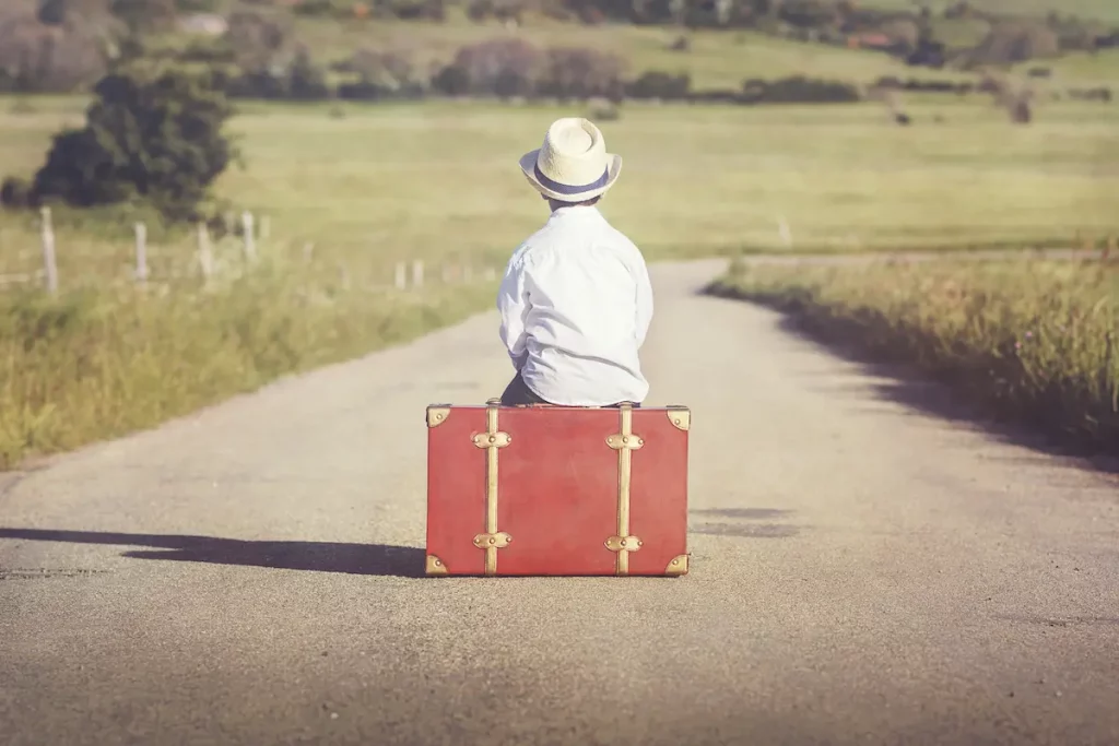 child with no family sitting on road with luggage