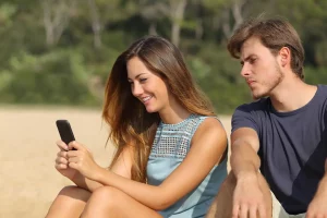Boyfriend looking over girlfriends shoulder at phone being jealous