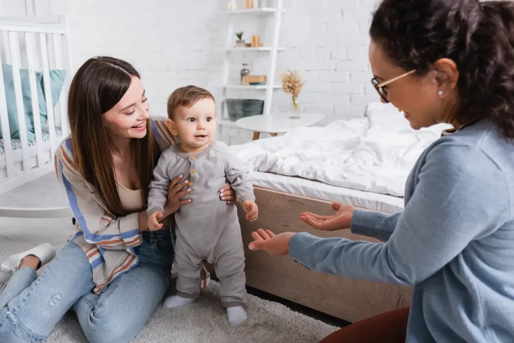 step-mom holding small boy helping him walk and co-parenting with biological mother and son