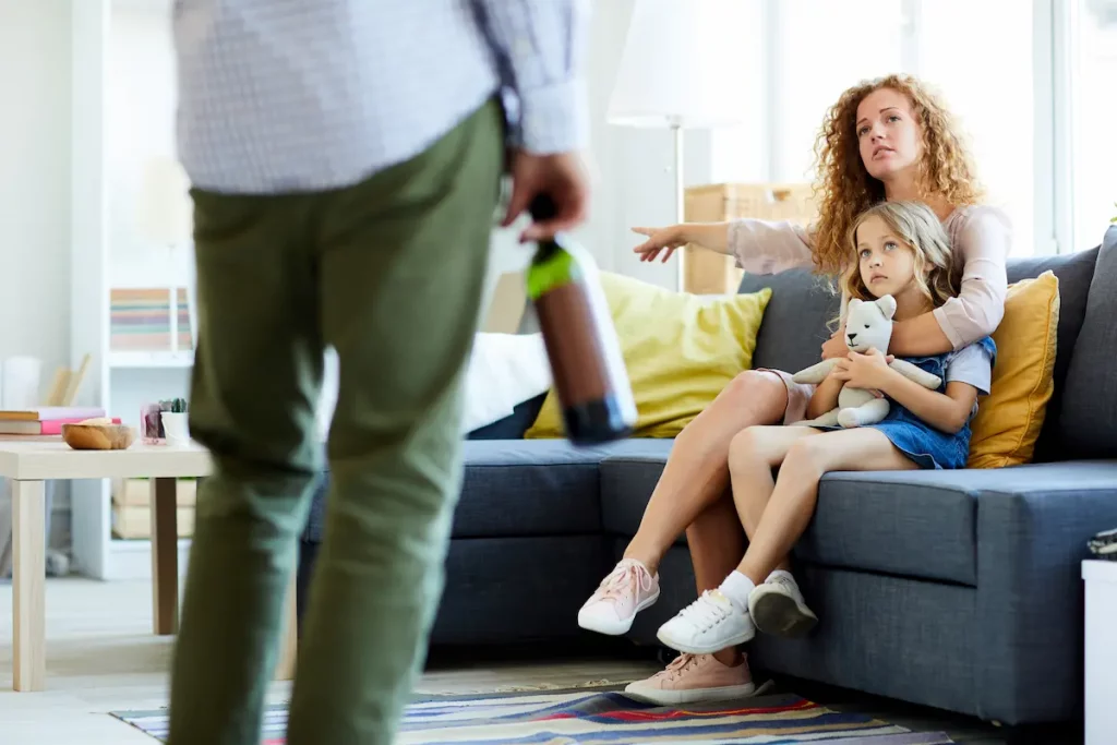 co-parents arguing as father is holding bottle of wine indicating he's been drinking