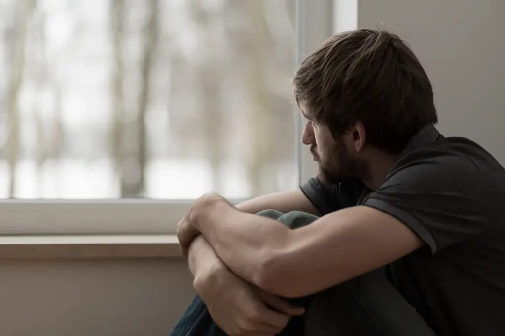 sad young man looking out window