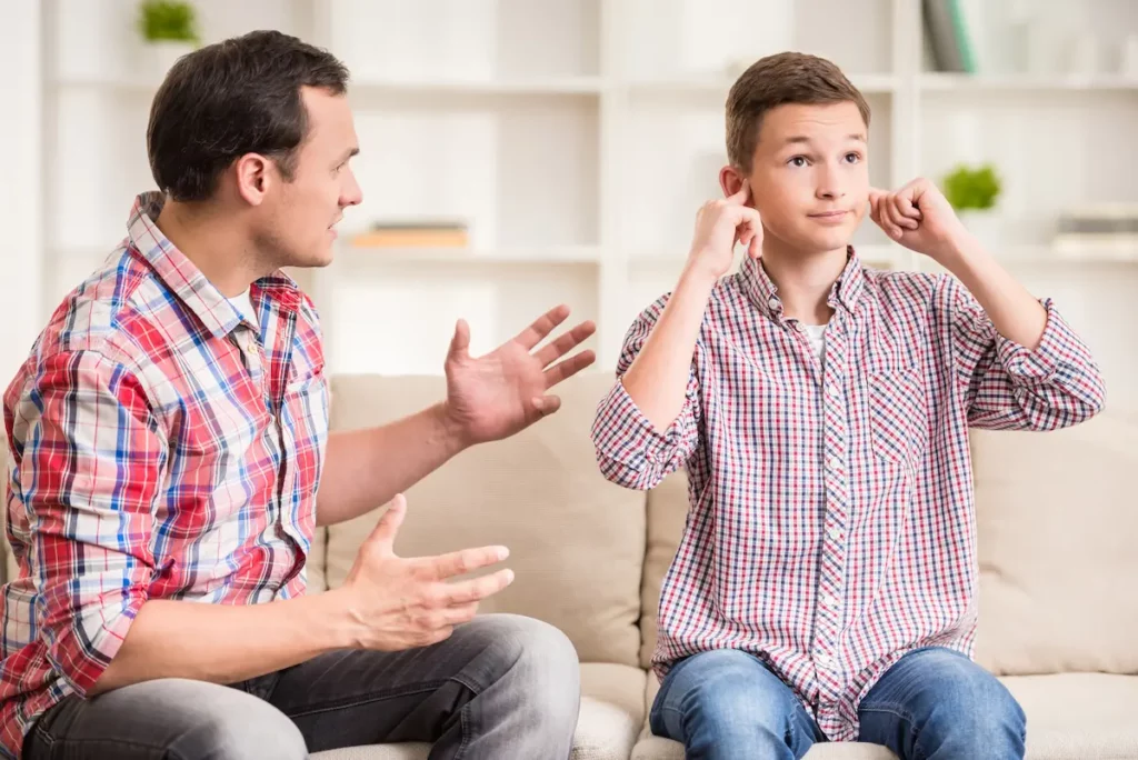 Young boy plugging ears next to dad to show he doesn't like him