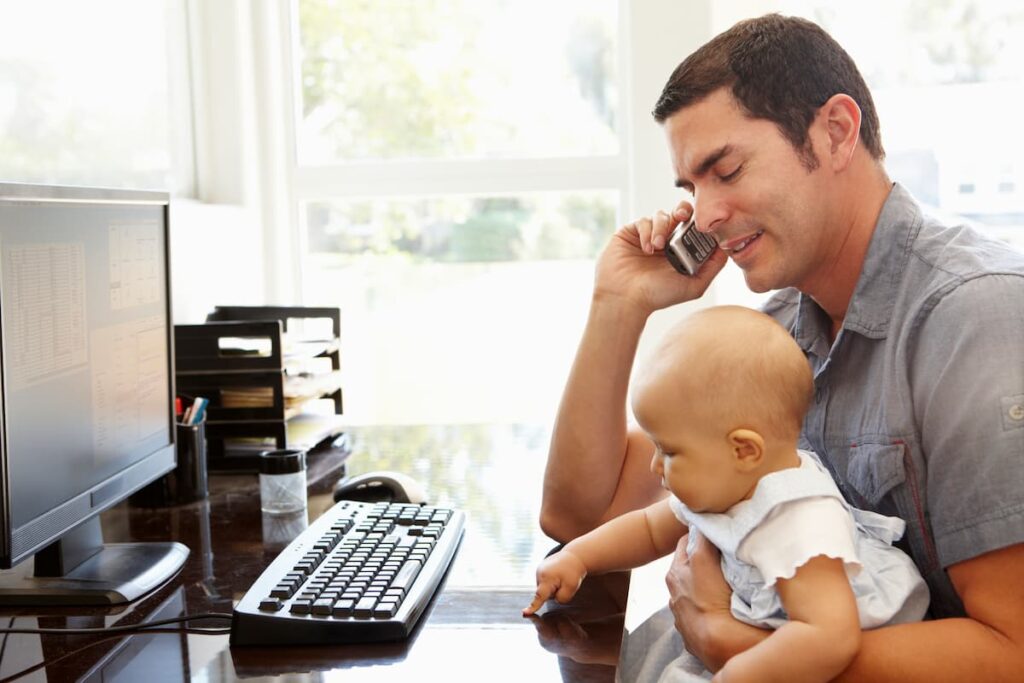 Dad up and working with baby on lap in the morning