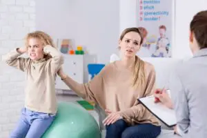 Child disrespecting parent in doctors office by covering ears with both hands