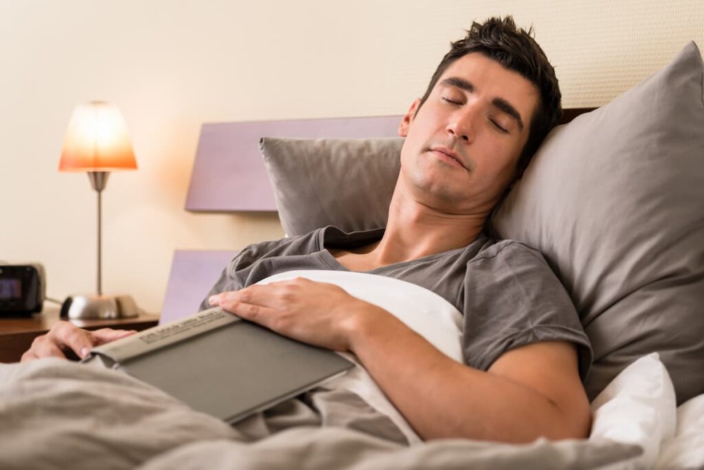 Man in bed falling asleep instantly while reading