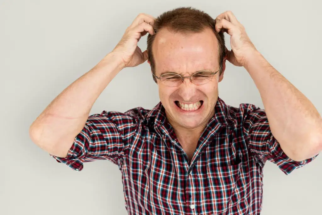 Man irritated and set off by small things and clawing his head