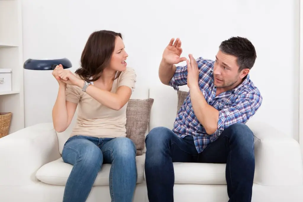 Girlfriend holding frying pan on couch about to hit boyfriend