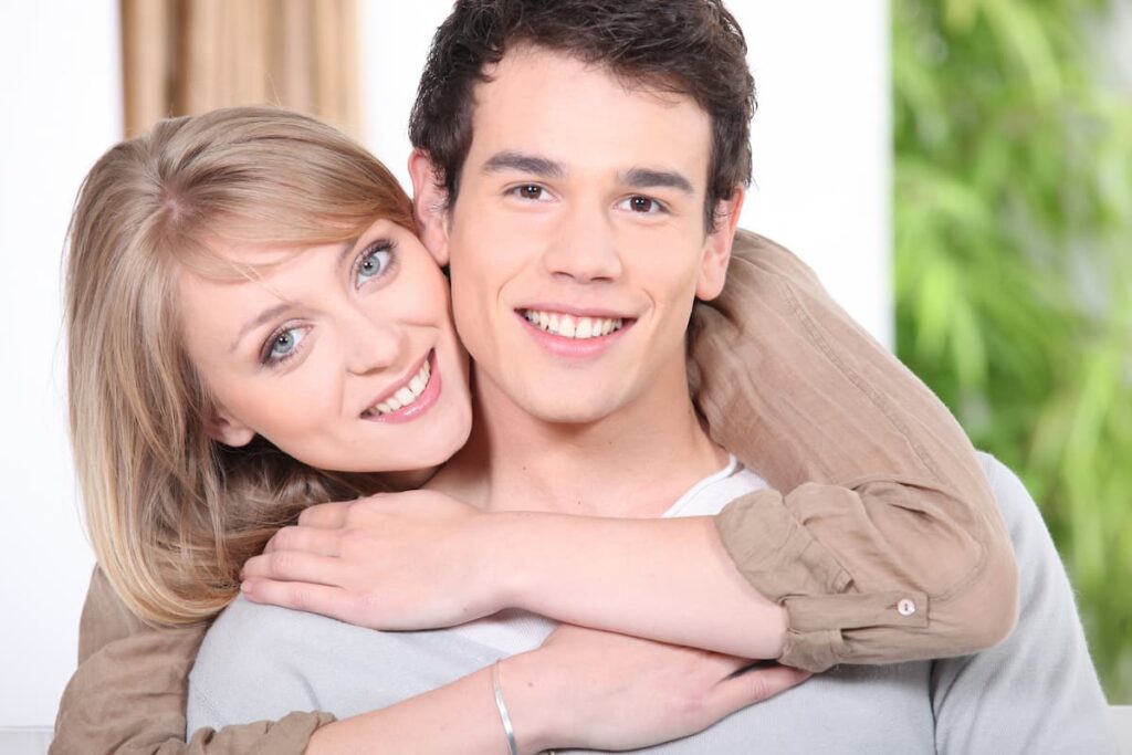 older woman dating younger man with her arms wrapped around him